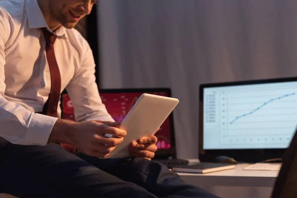 Vue recadrée de la tablette numérique dans les mains de l'homme d'affaires sur fond flou dans le bureau en soirée — Photo de stock