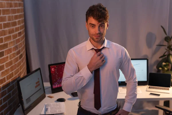 Geschäftsmann blickt abends im Büro auf Kamera in der Nähe von Computern — Stockfoto