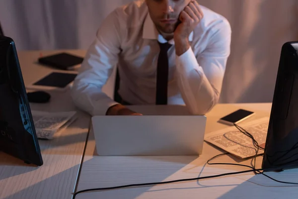 Vista cortada de laptop e computadores perto de empresário no fundo embaçado no escritório — Fotografia de Stock