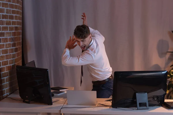 Homem de negócios gritando em pé perto de computadores no escritório durante a noite — Fotografia de Stock