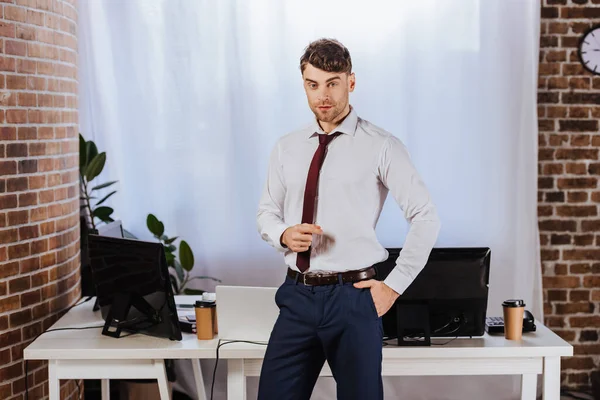 Jovem empresário com a mão no bolso de pé no escritório — Fotografia de Stock