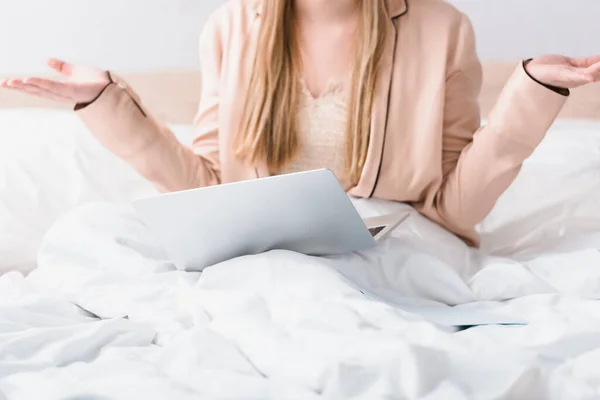 Ausgeschnittene Ansicht eines verwirrten Freelancer im Seidenmantel, der neben Laptop im Schlafzimmer gestikuliert — Stockfoto