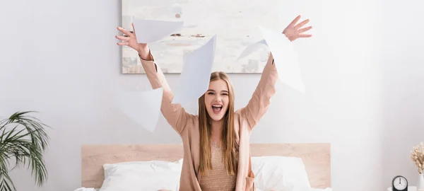 Mujer excitada en bata de seda lanzando documentos en el aire, bandera - foto de stock