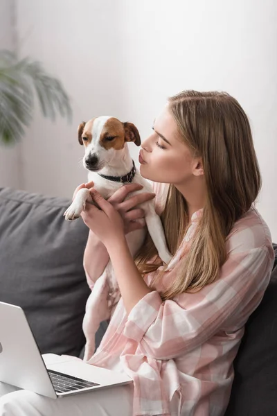 Jovem mulher segurando nos braços e beijando jack russell terrier — Fotografia de Stock