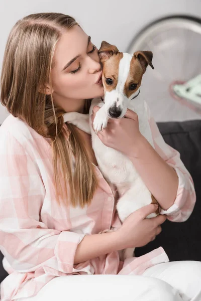 Junge Frau hält sich in den Armen und küsst Jack Russell — Stockfoto