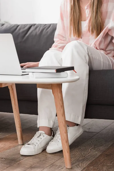 Обрізаний вид фрілансера, що сидить на дивані і використовує ноутбук — стокове фото