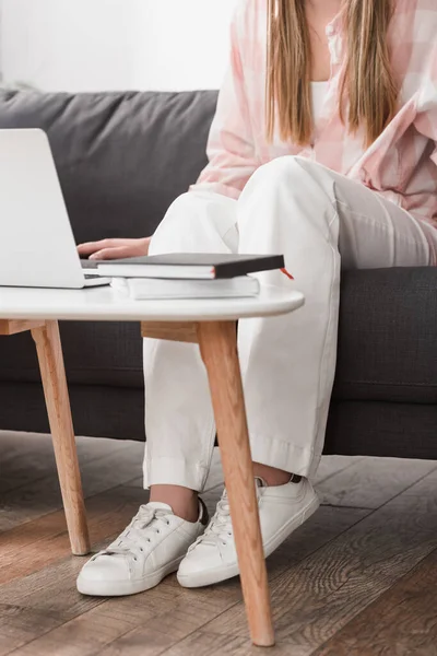 Ausgeschnittene Ansicht eines Freiberuflers, der auf der Couch sitzt und Laptop benutzt — Stockfoto