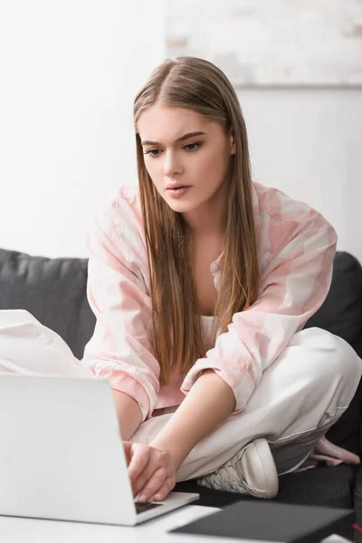 Focused freelancer sitting on couch and using laptop — Stock Photo