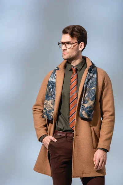 Homem na moda em casaco de inverno de pé com a mão no bolso em cinza — Fotografia de Stock