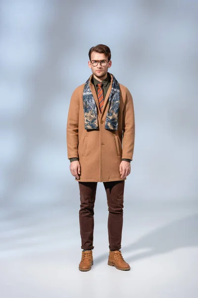 Longueur totale de l'homme élégant en manteau d'hiver debout en bottes sur gris — Photo de stock