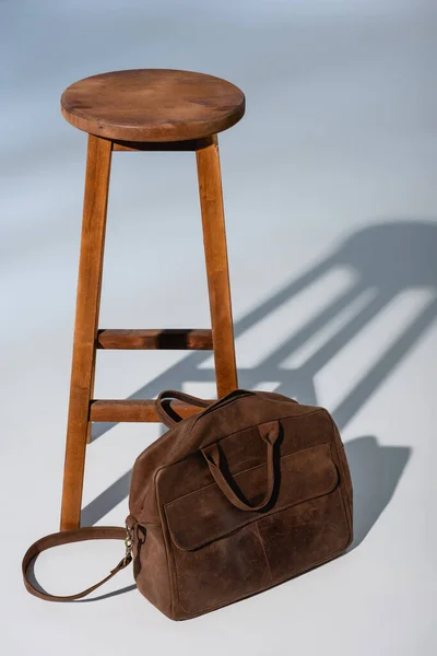 Шкіряний портфель біля дерев'яного стільця на сірому — стокове фото