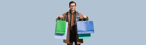 Heureux client dans des lunettes tenant des sacs en papier isolés sur gris, bannière — Photo de stock
