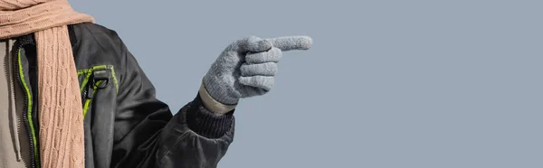 Vista parcial del hombre en guante apuntando con el dedo aislado en gris, bandera - foto de stock