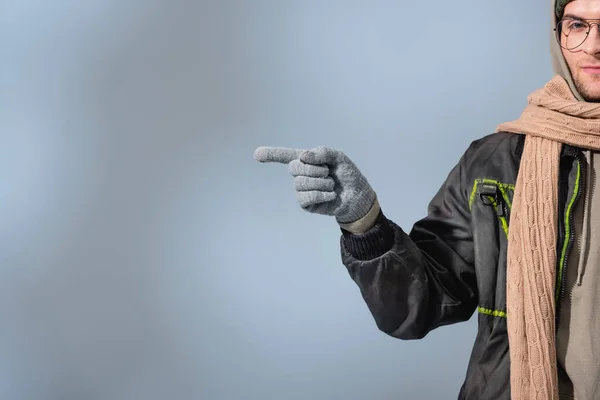 Vista recortada del hombre en gafas y parka señalando con el dedo en gris - foto de stock