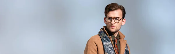 Trendsetter mit Brille, Schal und Wintermantel schaut weg auf Grau, Banner — Stockfoto