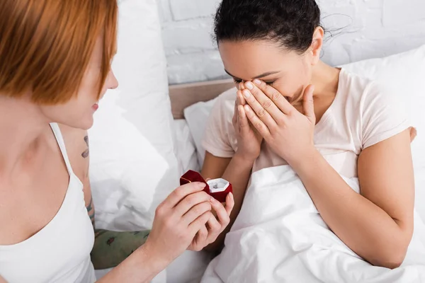 Eccitata donna afro-americana che copre il viso con le mani vicino alla ragazza lesbica facendo proposta di matrimonio — Foto stock