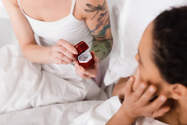 Cropped view of tattooed lesbian woman making wedding proposal to african american girlfriend on blurred foreground — Stock Photo