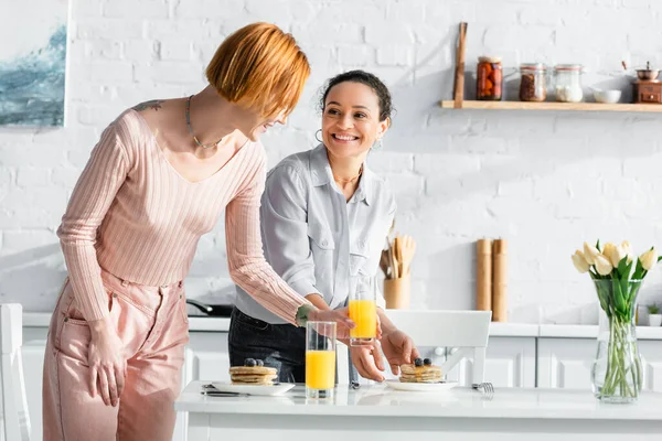 Alegre interracial lésbicas casal servindo café da manhã na cozinha — Fotografia de Stock