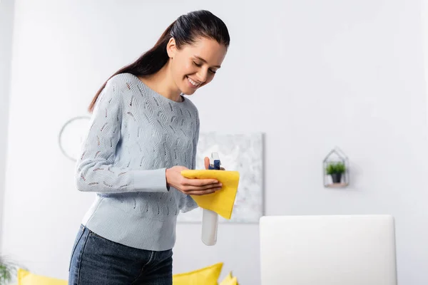 Cheerful housewife applying detergent on rag from spray bottle — Stock Photo