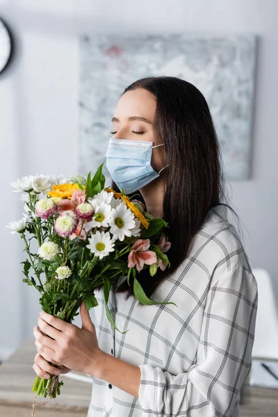 Young allergic woman in medical mask holding bouquet with closed eyes — Stock Photo
