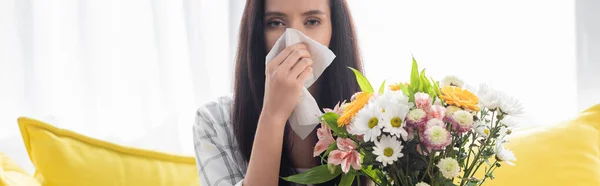 Allergic woman wiping nose with paper napkin near flowers, banner — Stock Photo