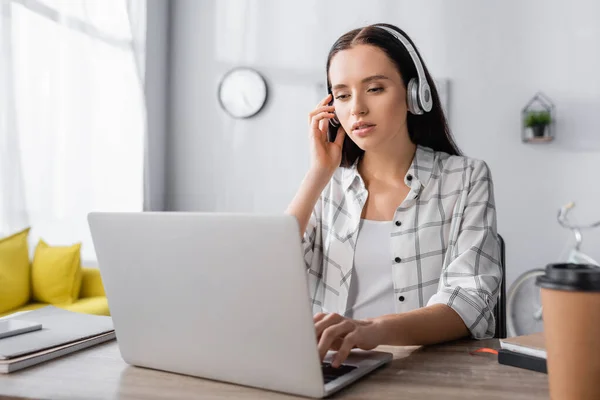Young freelancer in headphones typing on laptop at home — Stock Photo