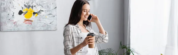 Mujer feliz hablando en el teléfono móvil mientras sostiene el café para llevar, pancarta - foto de stock