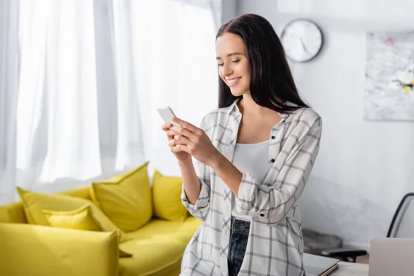 Mulher alegre mensagens no smartphone em casa — Fotografia de Stock