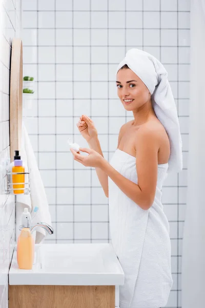 Щаслива жінка посміхається на камеру, тримаючи зубну нитку у ванній — стокове фото