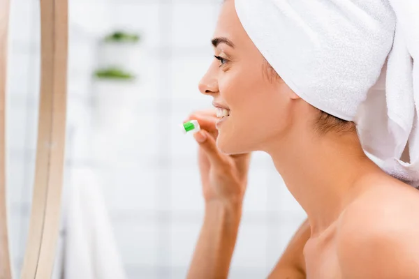 Вид сбоку женщины с белыми зубами на голове в ванной возле зеркала — стоковое фото