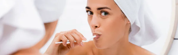 Giovane donna con asciugamano bianco sulla testa lavarsi i denti in bagno, primo piano sfocato, banner — Foto stock