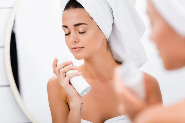 Young woman with closed eyes smelling deodorant in bathroom, blurred foreground — Stock Photo