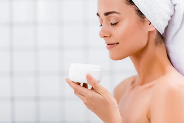 Heureux femme appréciant saveur de crème cosmétique avec les yeux fermés dans la salle de bain — Photo de stock