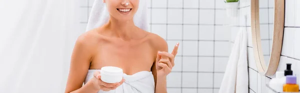 Vista ritagliata di giovane donna con crema viso sul naso sorridente in bagno, banner — Foto stock