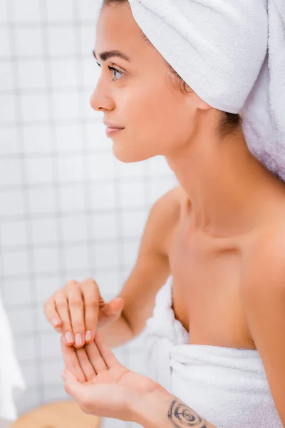 Молода жінка з ідеальною шкірою і білим махровим рушником на голові у ванній — стокове фото