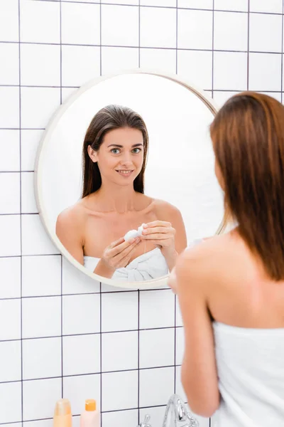 Smiling woman holding dental floss near mirror in bathroom, blurred foreground — Stock Photo