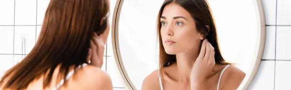 Young woman with perfect skin looking in mirror in bathroom, blurred foreground, banner — Stock Photo