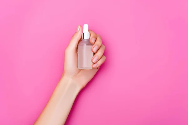 Vue du dessus de la main féminine toilettée avec bouteille de décapant pour cuticules sur fond rose — Photo de stock