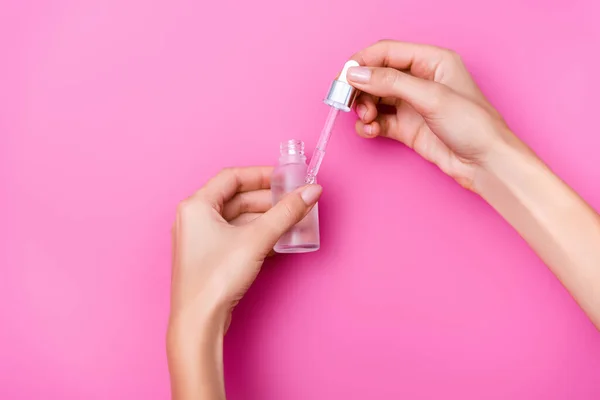 Vista ritagliata della donna in possesso di bottiglia di rimozione cuticola con contagocce su sfondo rosa — Foto stock