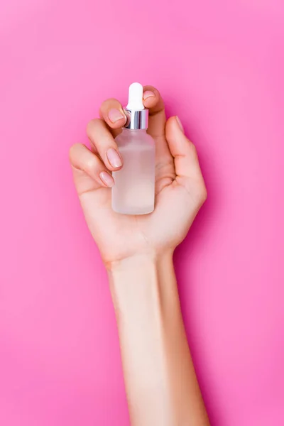 Top view of groomed female hand with vial of cuticle remover on pink background — Stock Photo