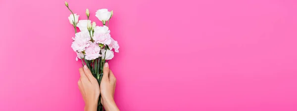 Vista recortada de la mujer con uñas pastel con clavel y flores de eustoma sobre fondo rosa, pancarta - foto de stock