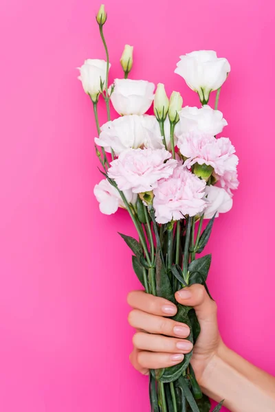 Частковий вид жінки з манікюром, що тримає букет з гвоздик та квітів еустоми на рожевому фоні — стокове фото