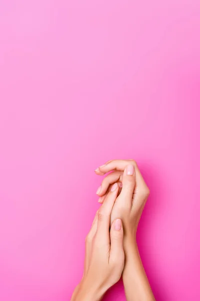 Top view of female hands with fingernails covered with pastel enamel on pink background — Stock Photo