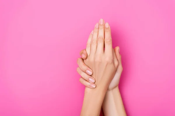 Vue du haut des mains féminines avec manucure pastel sur fond rose — Photo de stock