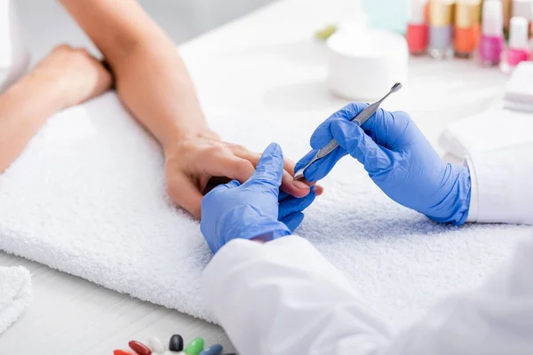 Foyer sélectif du poussoir de cuticule dans les mains de manucure faisant manucure au client, vue recadrée — Photo de stock