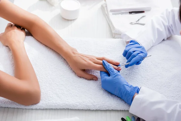 Partial view of manicurist making manicure to woman with cuticle pusher — Stock Photo