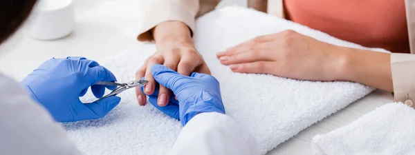 Foyer sélectif de la pince à cuticule dans les mains de manucure faisant manucure au client, vue recadrée, bannière — Photo de stock