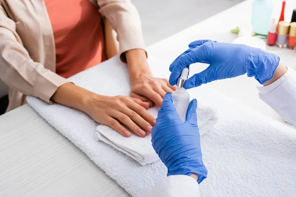 Partial view of manicurist holding cuticle remover near client in nail salon — Stock Photo