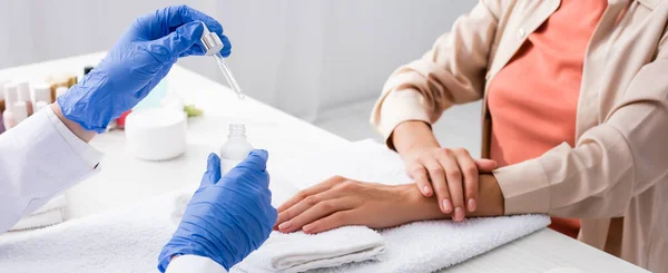 Partial view of manicurist holding dropper and cuticle remover near client, banner — Stock Photo