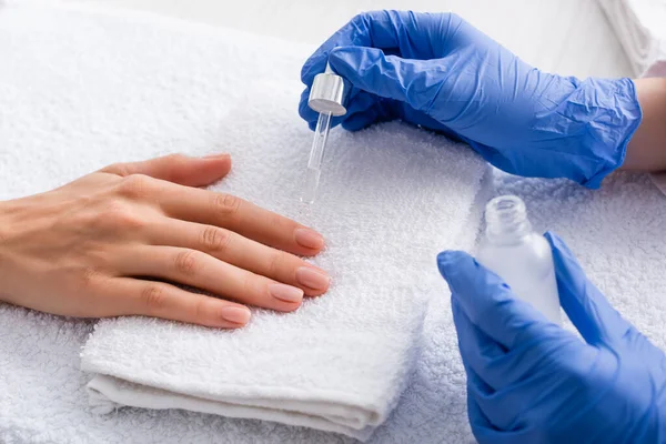 Partial view of manicurist applying cuticle remover while making manicure to client — Stock Photo